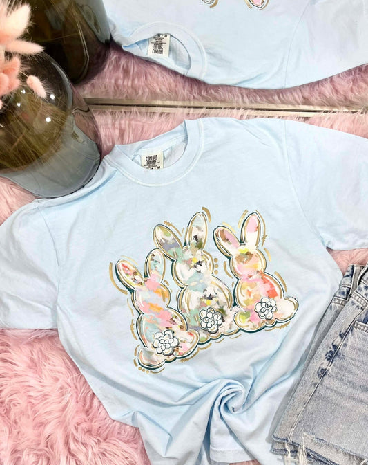 Light blue t-shirt with water color brushed floral bunny design on a pink surface